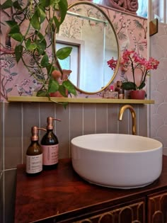 a bathroom sink sitting under a mirror next to a wooden counter top with bottles on it