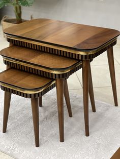 three wooden tables sitting on top of a white rug next to a potted plant