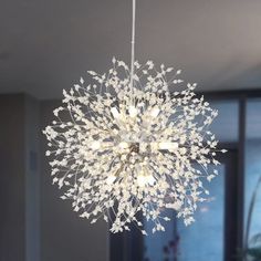 a white chandelier hanging from a ceiling in a living room with glass doors