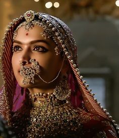 a woman in a red and gold outfit with her nose ring on top of her head