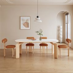 a dining room table with four chairs and a vase on the table in front of it