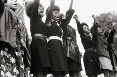 black and white photograph of women singing with hands in the air