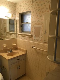 a bathroom with a sink, mirror and toilet in it's corner area next to a window