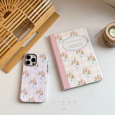 two iphone cases sitting next to each other on a white table with a bamboo holder