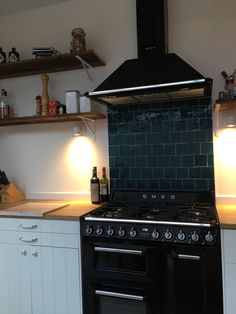 a black stove top oven sitting inside of a kitchen next to white cupboards and shelves