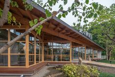 a wooden building with glass walls and trees in the background