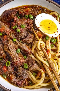 a bowl filled with noodles, meat and an egg