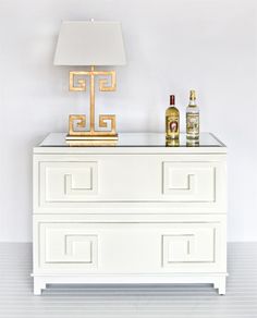 a white dresser with two bottles and a lamp on top