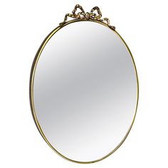 a round mirror with an ornate design on the top and bottom edge is shown in gold