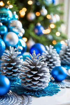 blue and silver christmas decorations on a table with a tree in the backround