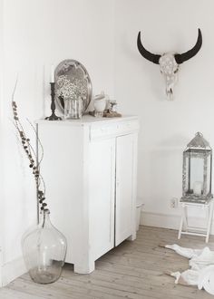 a room with a white cabinet, mirror and cow skull on the wall above it