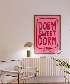 a pink poster hangs on the wall next to a white chair and side table with a potted plant