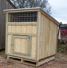 a small wooden shed sitting on top of a dirt field next to a building with a window