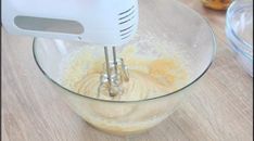 a hand mixer mixing batter in a glass bowl on top of a wooden countertop