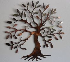 a metal tree with lots of leaves hanging from it's sides on a wall