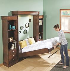 a woman vacuuming the floor in her bedroom with a bed and bookshelf