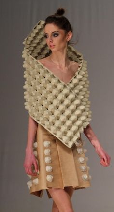 a woman is walking down the runway in a dress made out of egg cartons