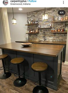 a kitchen island with three stools in front of it and shelves on the wall