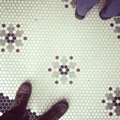 two pairs of purple shoes standing on a tiled floor with hexagonal tiles in the background