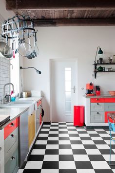 a black and white checkered floor in a kitchen with red accents on the cabinets