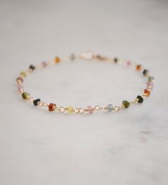 Spread creativity and joy with this multicolor gemstone Tourmaline bracelet! This handmade beauty features natural Tourmaline crystals in a variety of hues, including pink, black, green, and yellow. Each bracelet is unique, with no set pattern, making each one a one-of-a-kind. It comes in your choice of sterling silver or 14k gold filled. Tourmaline Meaning: The birthstone for October, Tourmaline is believed to promote inspiration, boost confidence, and combat fear. Stone Size: Average 3-4mm Mat Gold Gemstone Bracelet, Elegant Luxury Tourmaline Bracelets, Cute Beaded Bracelets, Tourmaline Meaning, Crystal Diy, Bracelets With Meaning, Beauty Features, Tourmaline Bracelet, Mix Of Colors