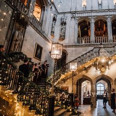 people are walking up and down the stairs in an old building with christmas lights on it