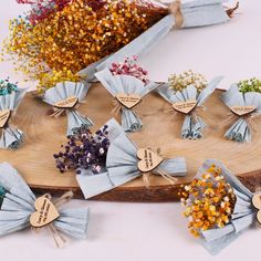 several pieces of paper tied together with wooden tags and small flowers on top of a piece of wood