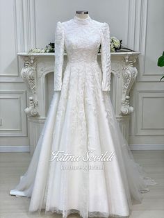 a white wedding dress on display in front of a table with flowers and greenery