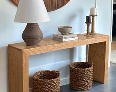 a wooden table with two baskets underneath it and a lamp on the wall behind it