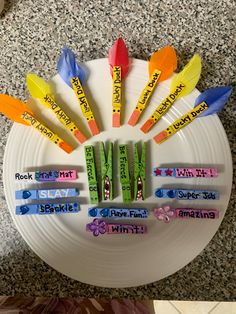 a white plate topped with lots of different colored markers on top of eachother