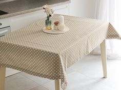 a kitchen table covered with a polka dot tablecloth and vases on top of it