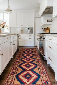 a rug in the middle of a kitchen with white cabinets and drawers on both sides