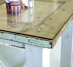 a wooden table with a glass top and two cups sitting on it's sides