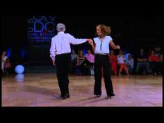 two people dancing on a dance floor with one holding the other's arm out