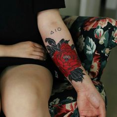 a woman's arm with a red flower tattoo on her left forearm and right leg