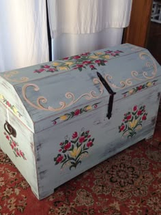 an old wooden chest with floral designs painted on the front and sides, sitting on a rug