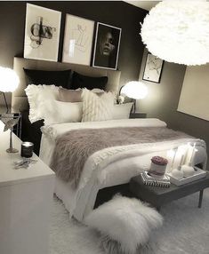 a white bed sitting next to two lamps and pictures on the wall