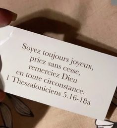 a person holding up a card with the words in french and english on it's side