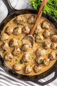 a skillet filled with meatballs and gravy next to some parsley