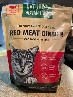 a bag of red meat dinner sitting on top of a counter next to a cat