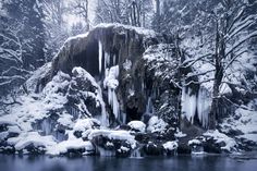 a frozen waterfall surrounded by snow covered trees