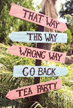 a wooden sign that says, that way wrong way go back tea party