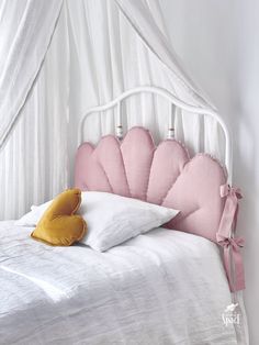 a white bed with pink and yellow pillows