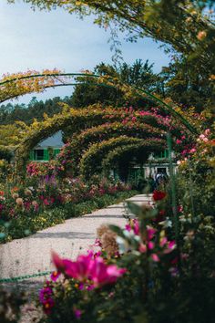 an arch covered in flowers next to a walkway