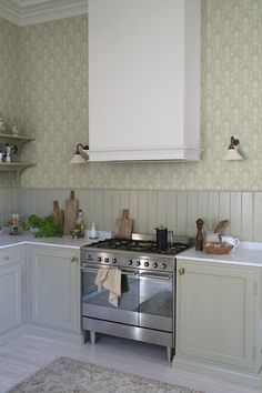 a stove top oven sitting inside of a kitchen next to a wallpapered wall