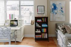 a living room filled with furniture and a book shelf next to a window covered in books