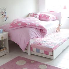 a bedroom with pink bedding and white furniture