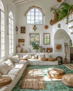 a living room filled with lots of furniture next to two large windows and potted plants