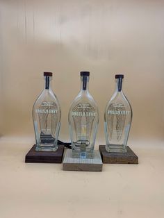 three glass bottles sitting on top of wooden bases