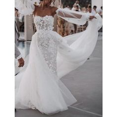 a woman in a white wedding dress walking down the street